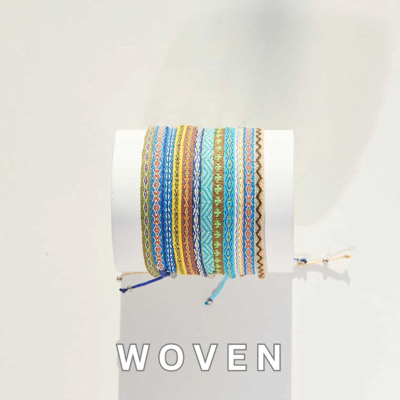 Colorful woven bracelets stacked on a white display cylinder in natural lighting