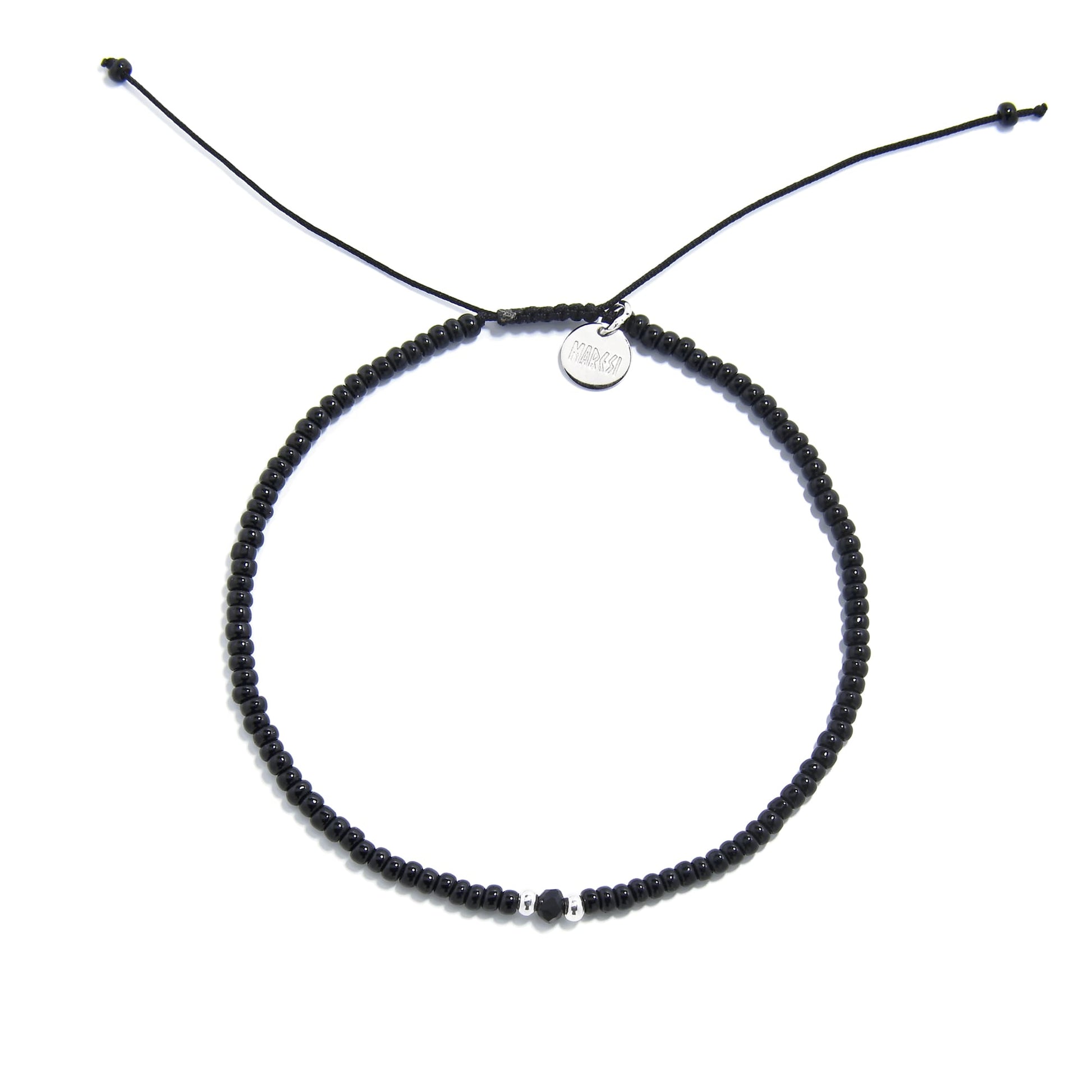 An adjustable mens beaded bracelet with black beads and a silver charm, lying flat on a white surface.