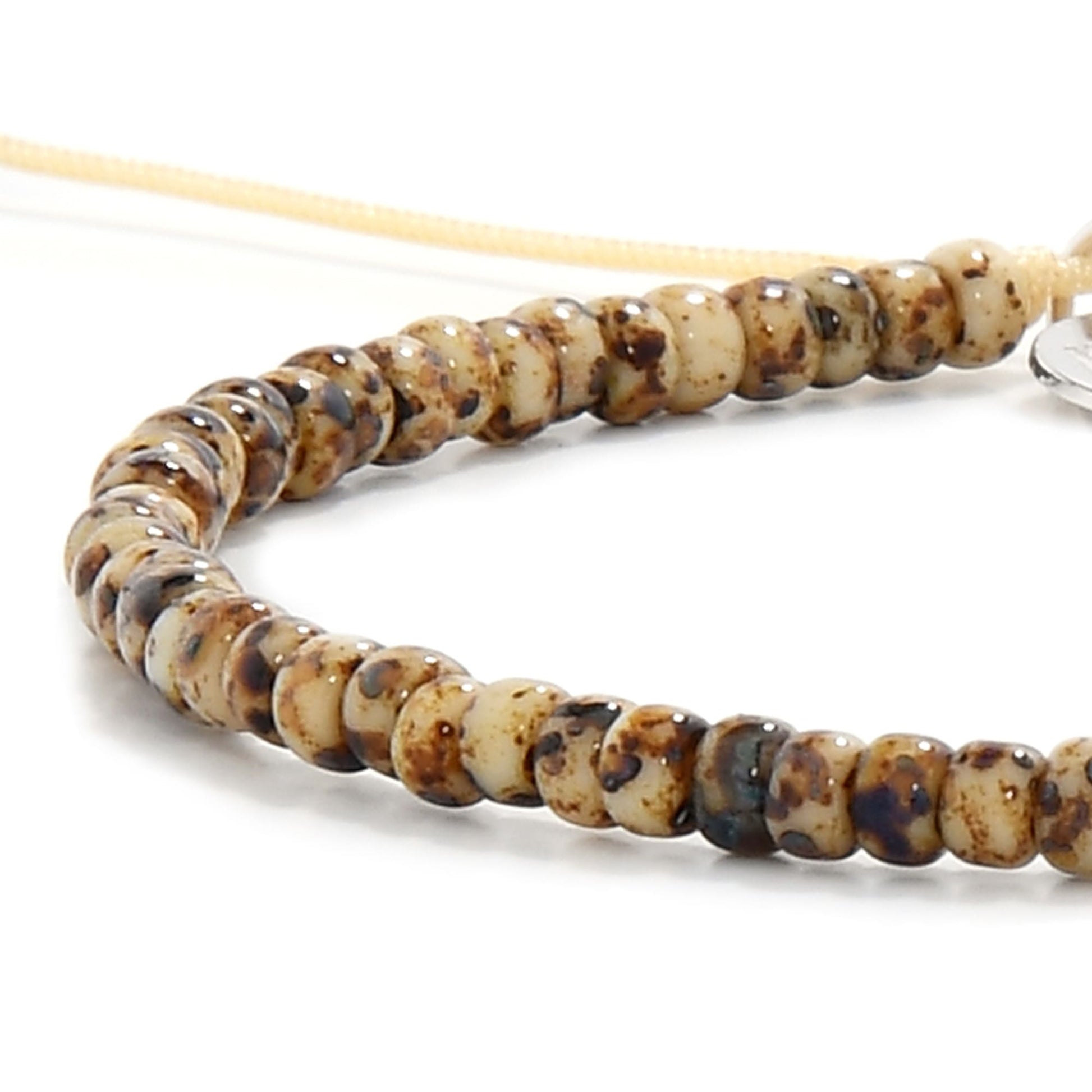 Close-up of bead bracelet for men with brown and cream speckled seed beads on tan cord