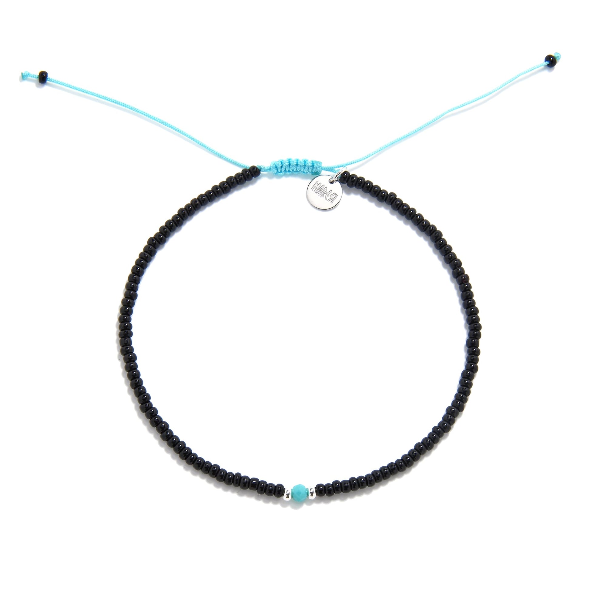 A round beaded bracelet with black beads and a striking turquoise bead in the center, shot from a top-down view on a white background.