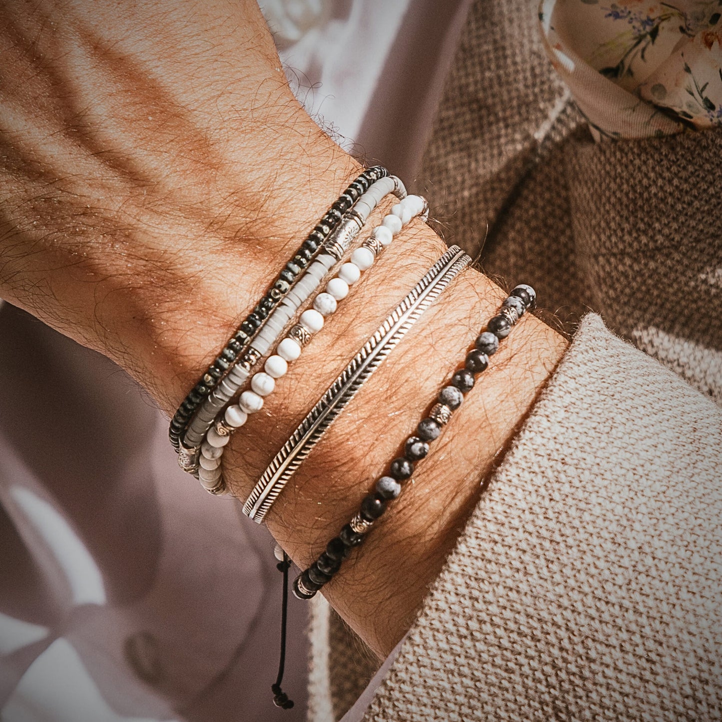 Stacked Cannes bracelet set featuring white beads, dark tones, and silver bands on a male wrist