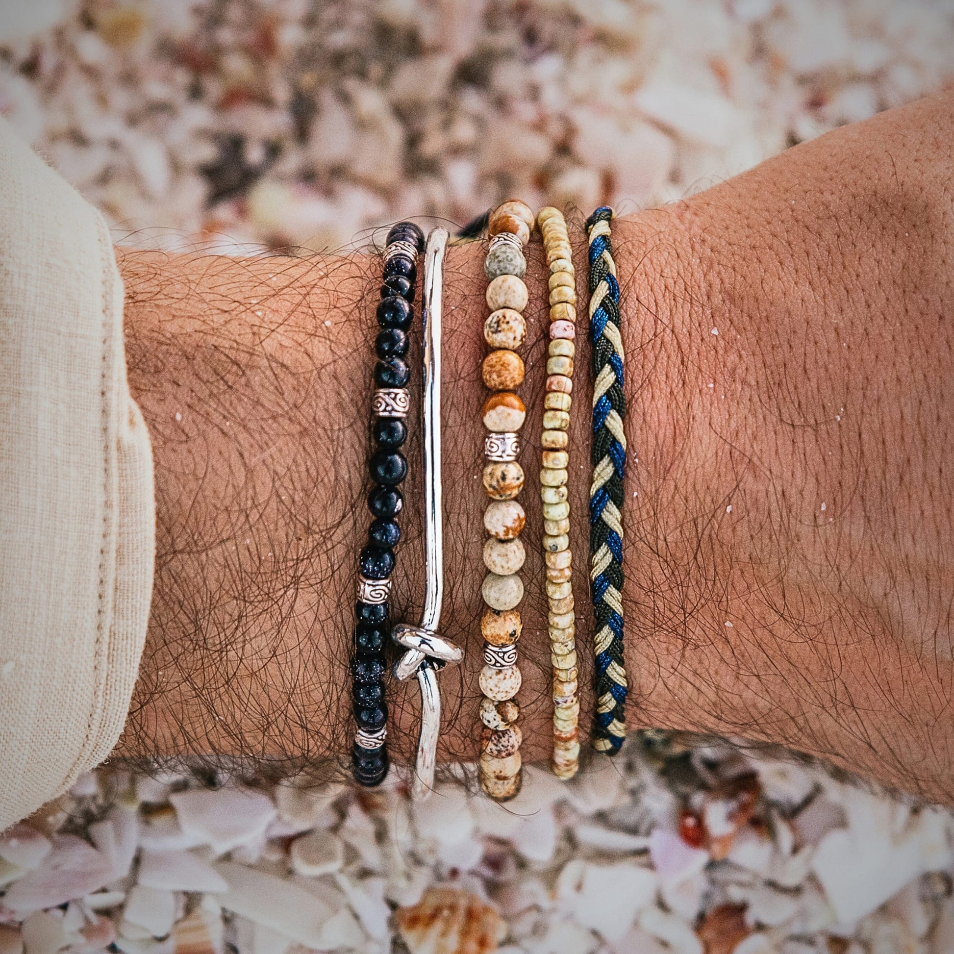 Close-up of a wrist with Capri bracelets on a background of seashells.