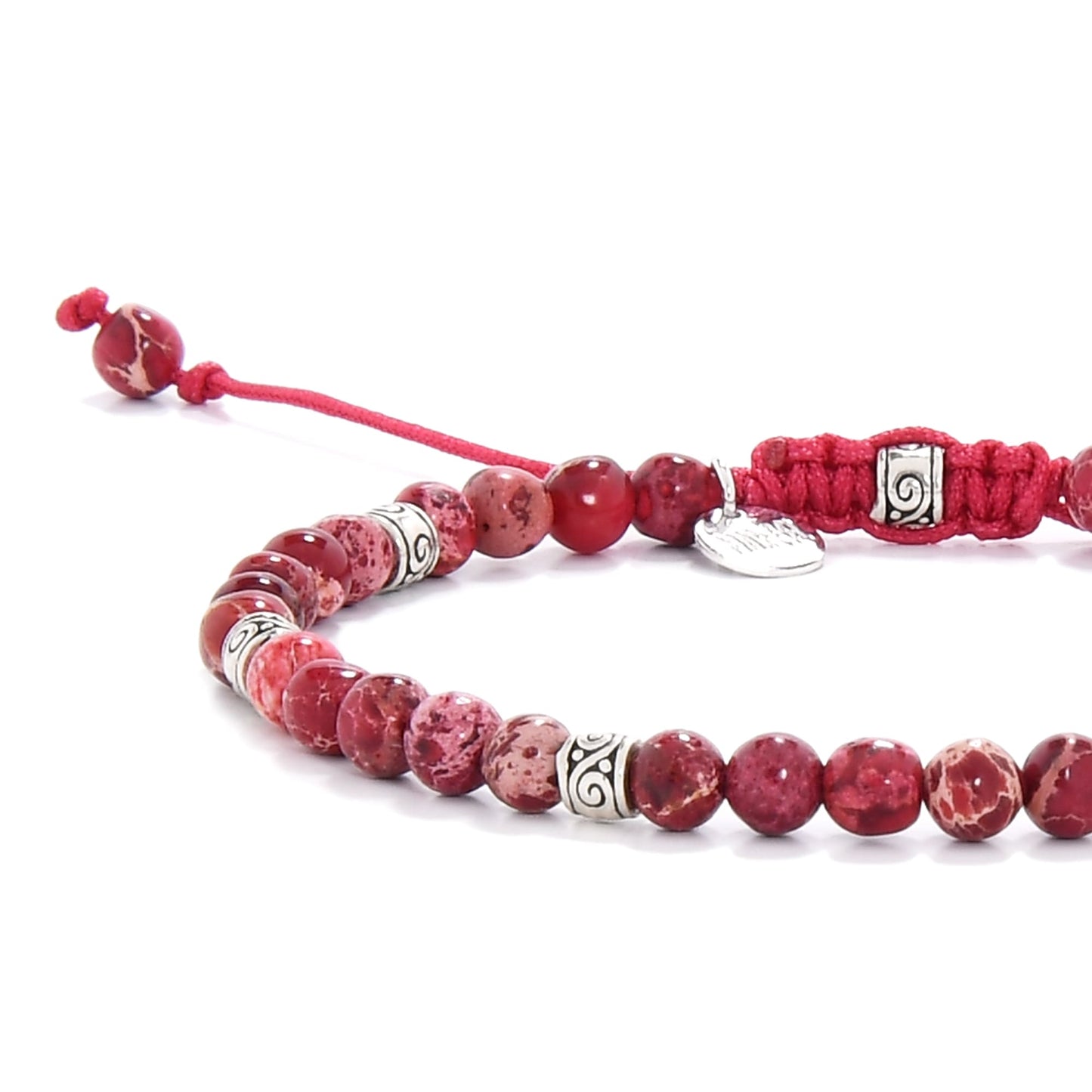 Red jasper bracelet detail highlighting polished gemstone beads and silver swirl-patterned spacers.