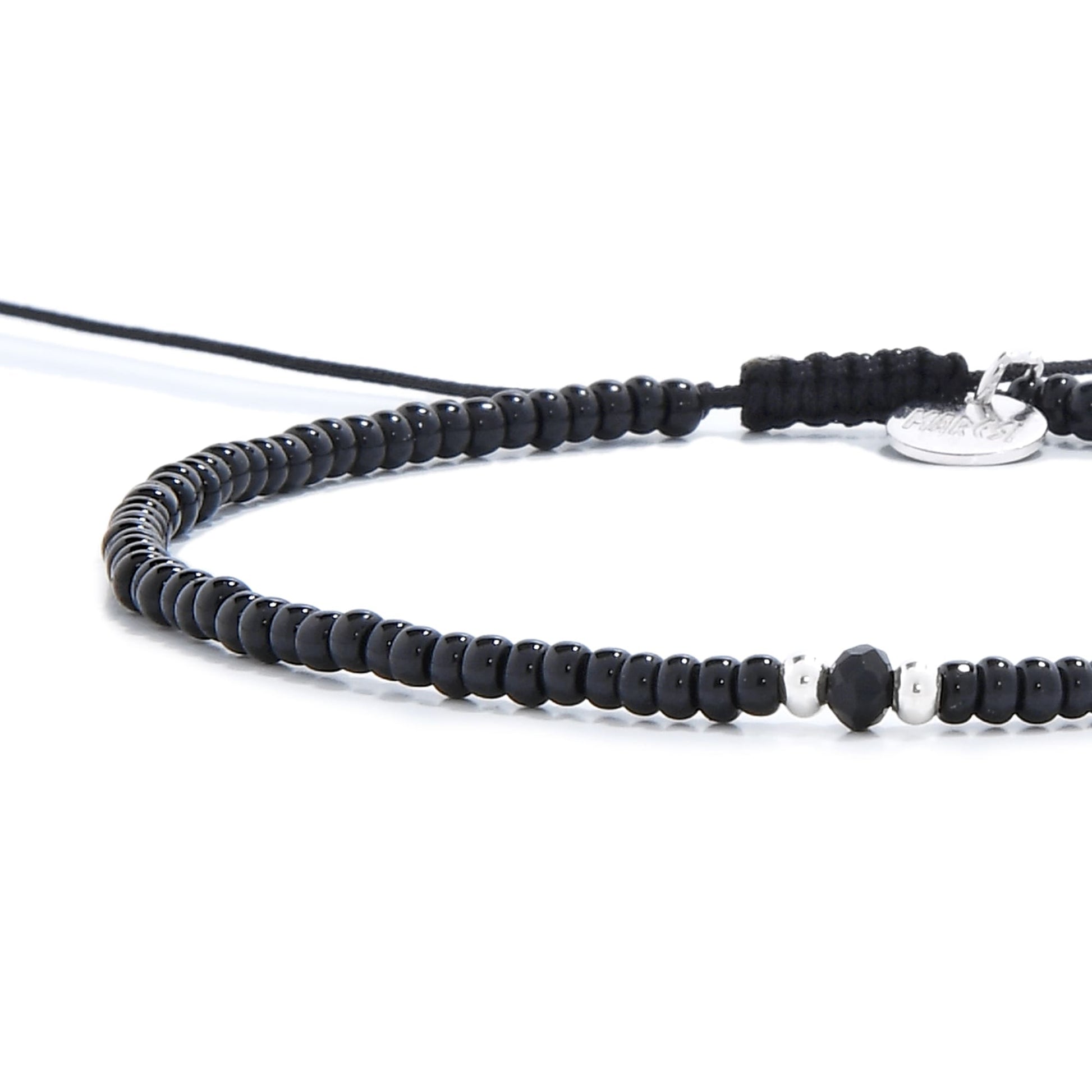 Close-up of a black mens beaded bracelet, showing a faceted onyx bead between two silver beads.