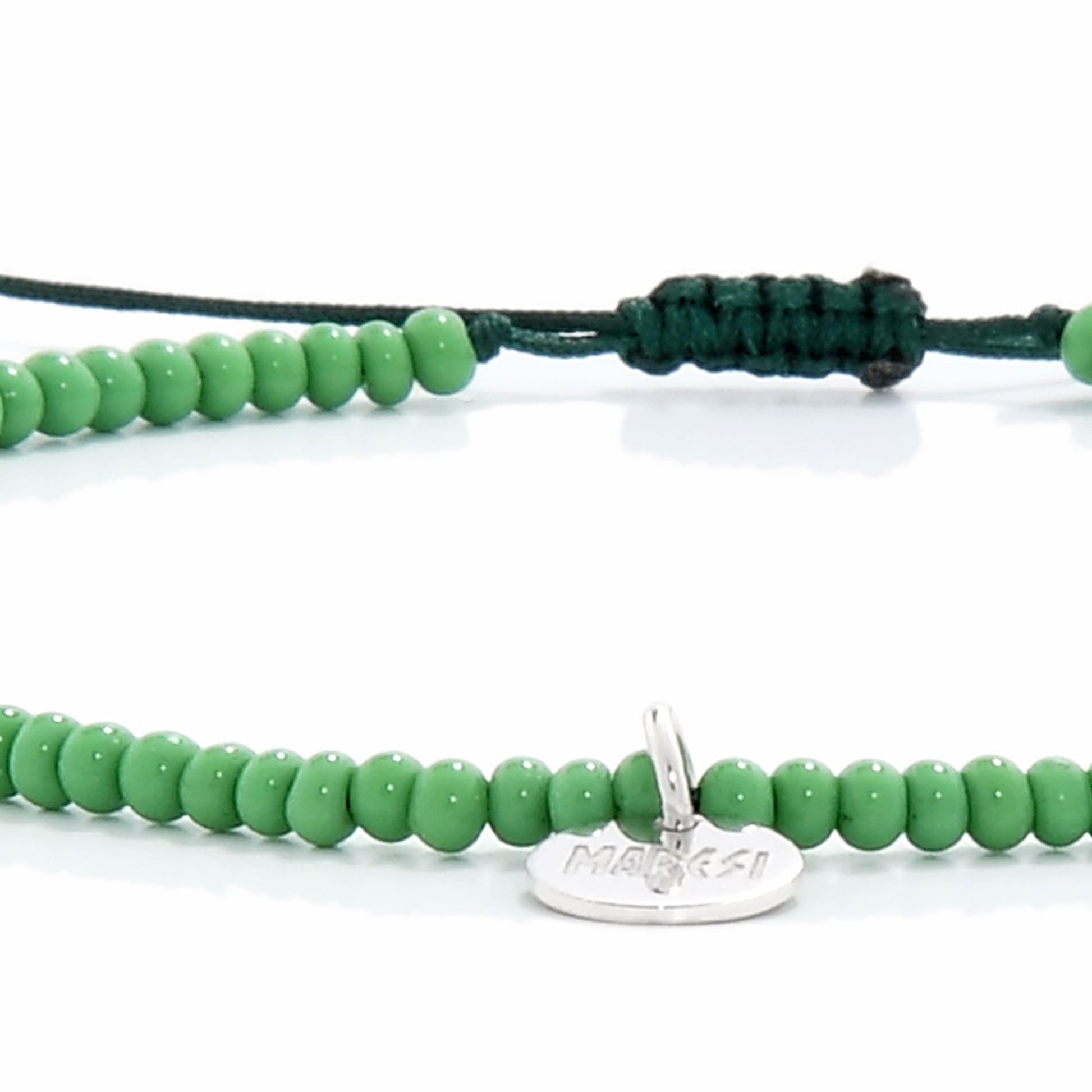 Detailed view of green beaded stretch bracelet with silver charm