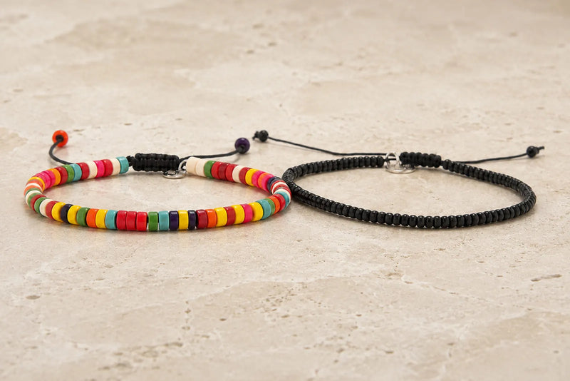 Colorful and black bracelet color combo featuring two slim bead bracelets on light travertine