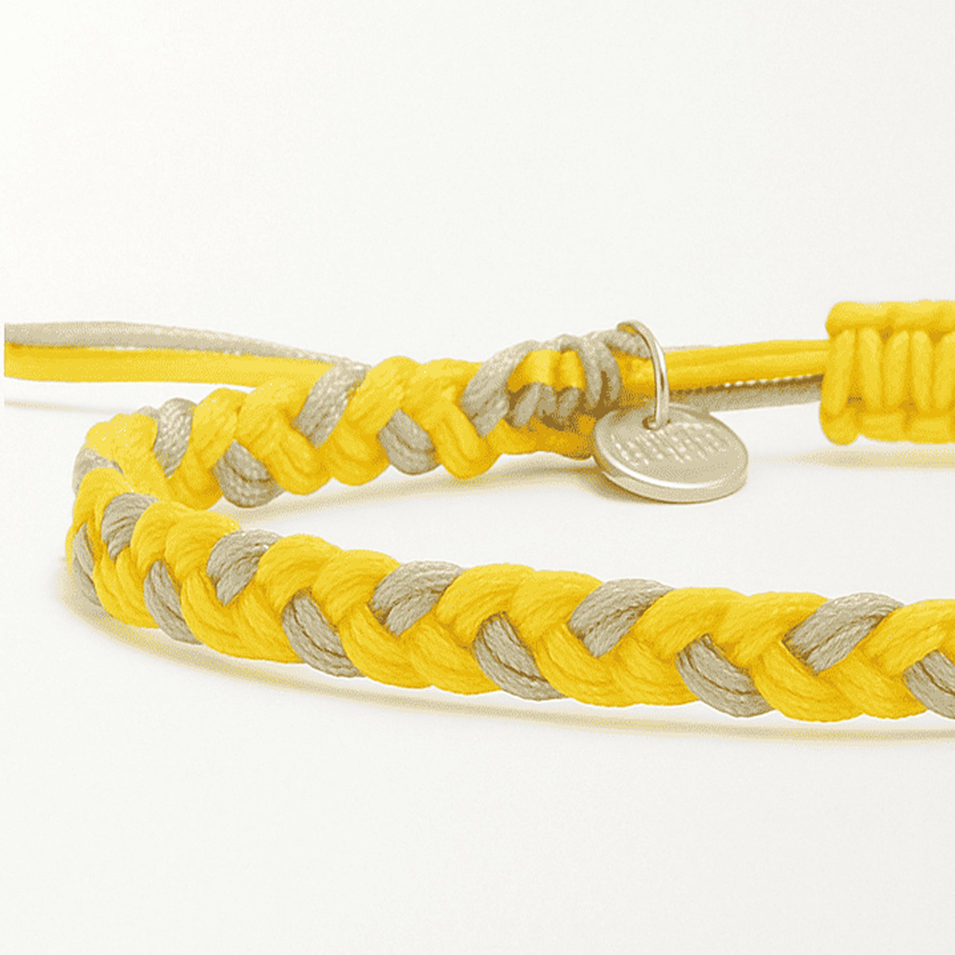 Close-up of friendship bracelet thread in yellow and gray with braided cord and charm