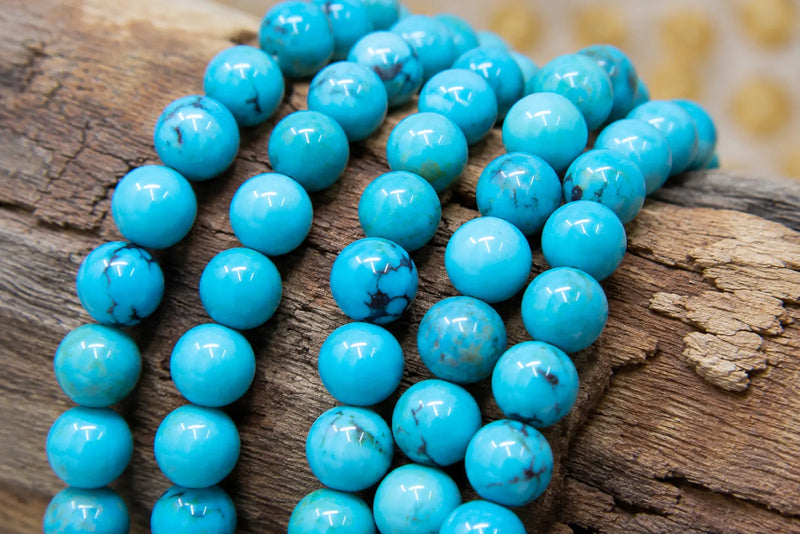 Genuine turquoise bracelet beads with natural veining arranged on rustic wood in a close-up jewelry photograph.