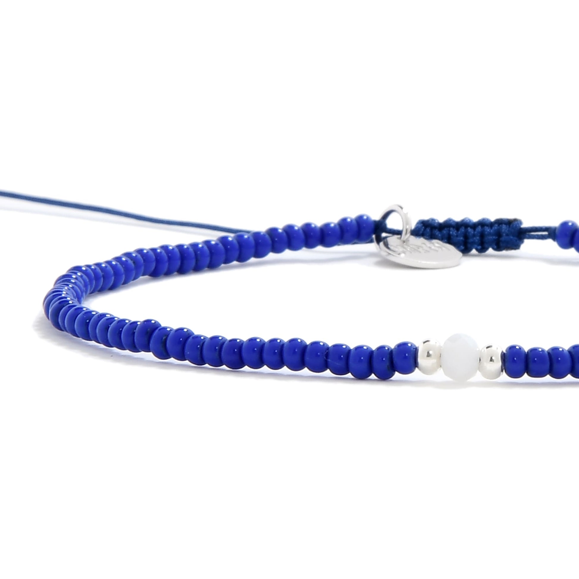 Handmade seed bead bracelet featuring glossy blue beads and white focal bead with silver