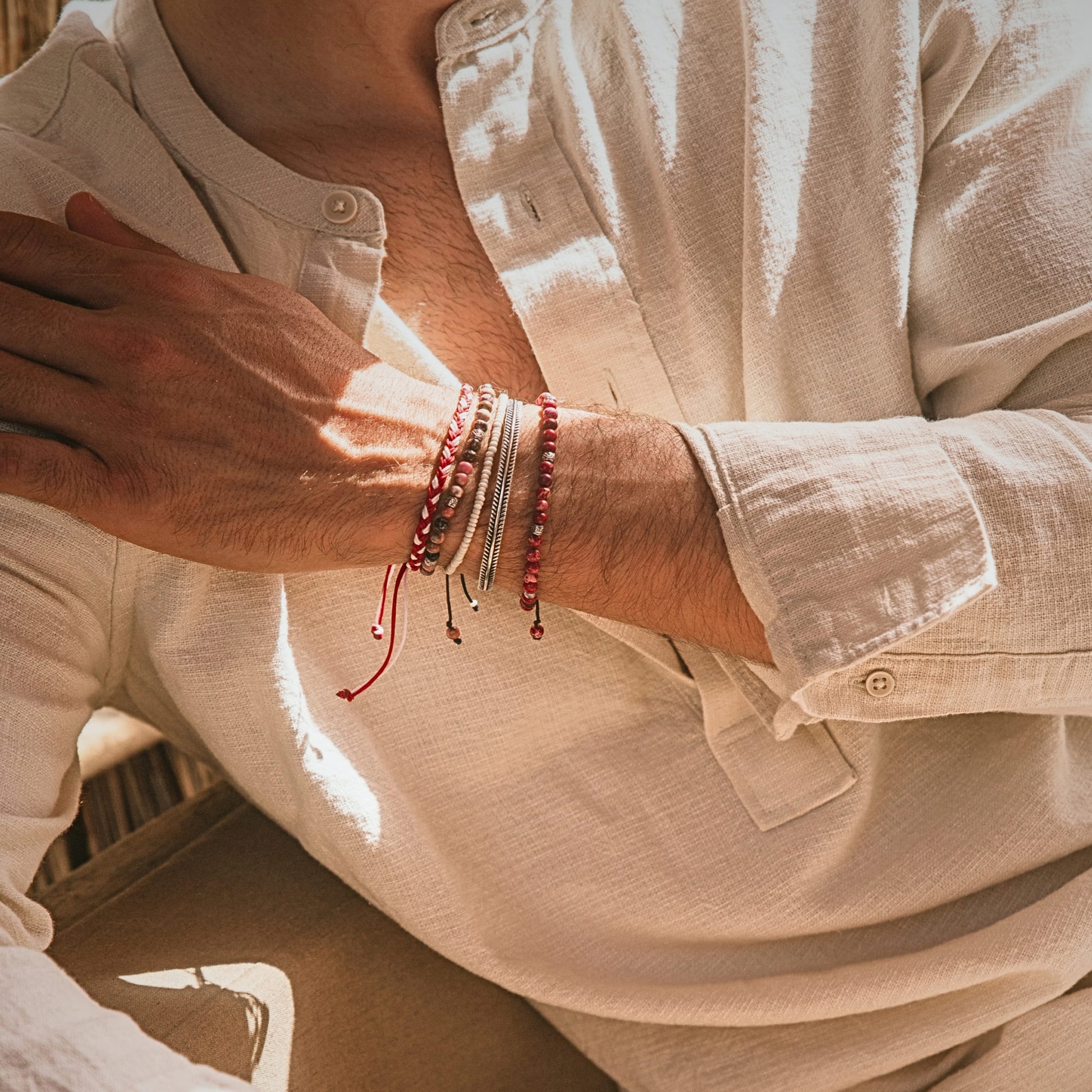 Man wearing Marseille stack bracelet with red beads and silver details, relaxed summer outfit