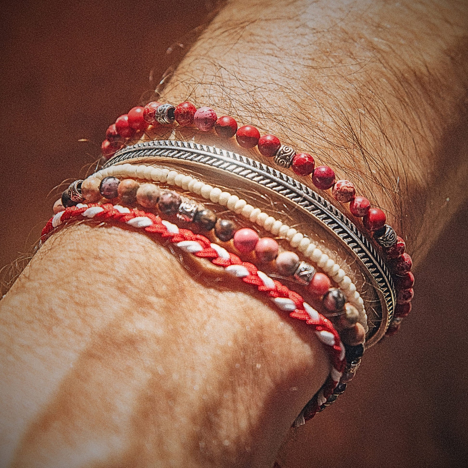Wrist adorned with Marseille bracelet set featuring red, cream, and silver tones