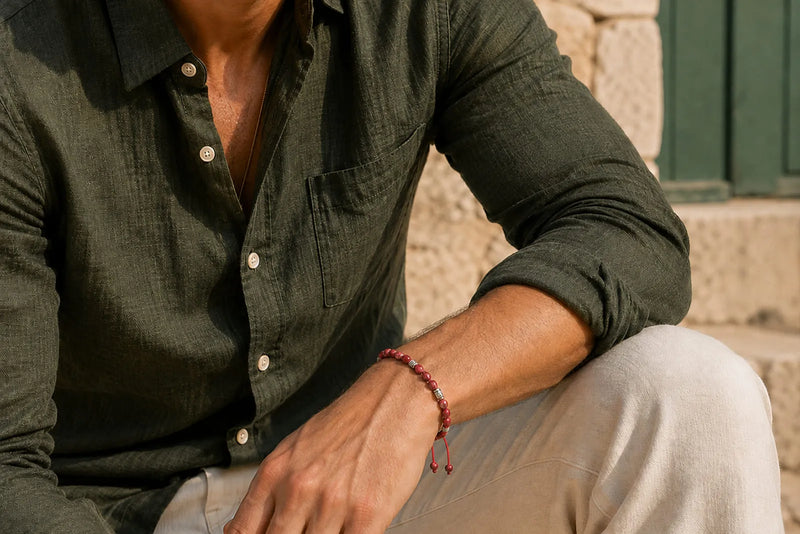 Man wearing a slim red beaded bracelet with an olive shirt and cream trousers for a coordinated casual look.