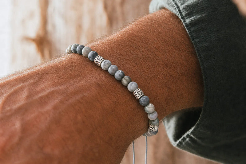 Men’s gray bead bracelet with polished marbled stones and engraved silver spacers shown in a close-up wrist view.