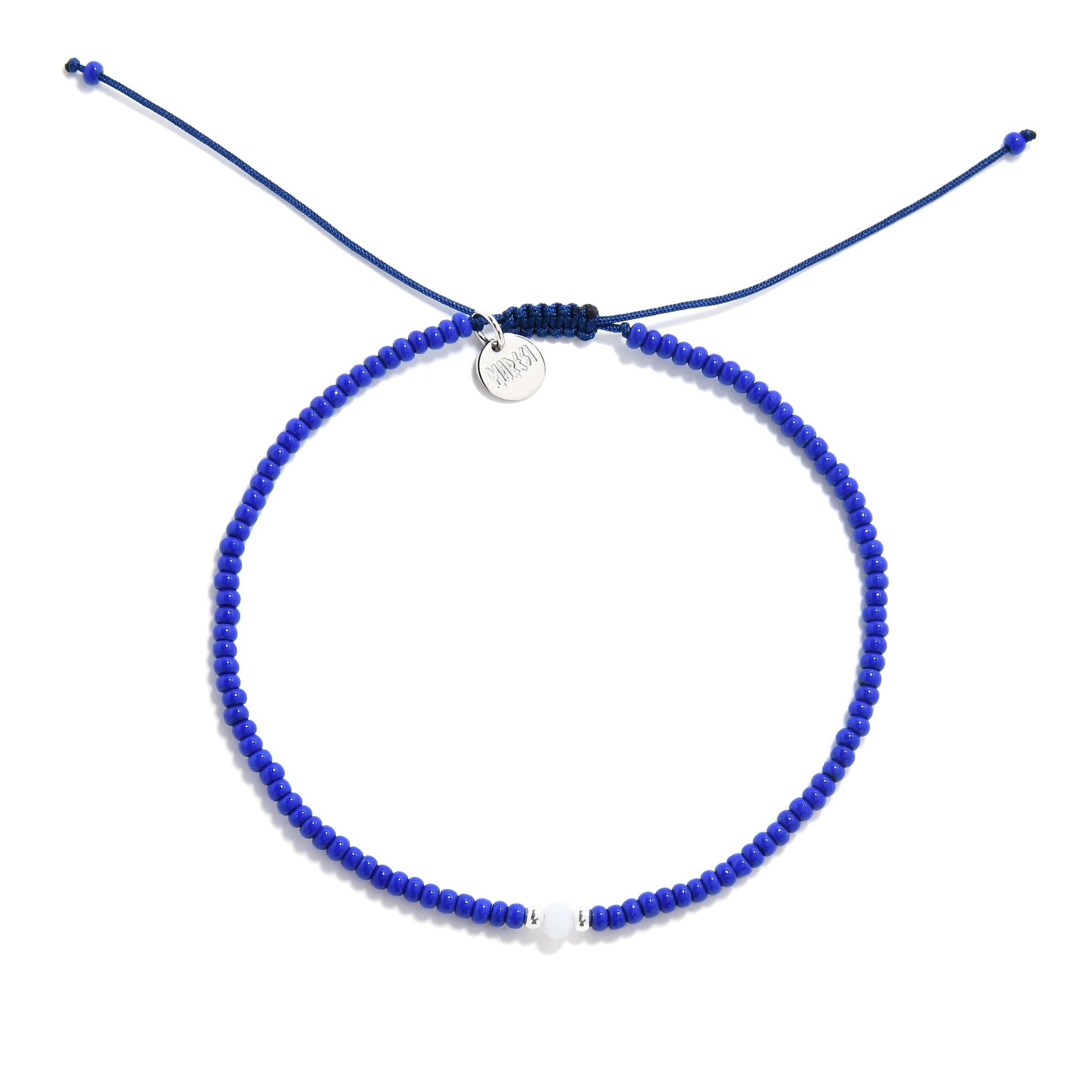 Flat lay of minimalist seed bead bracelet in blue with center white and silver accent
