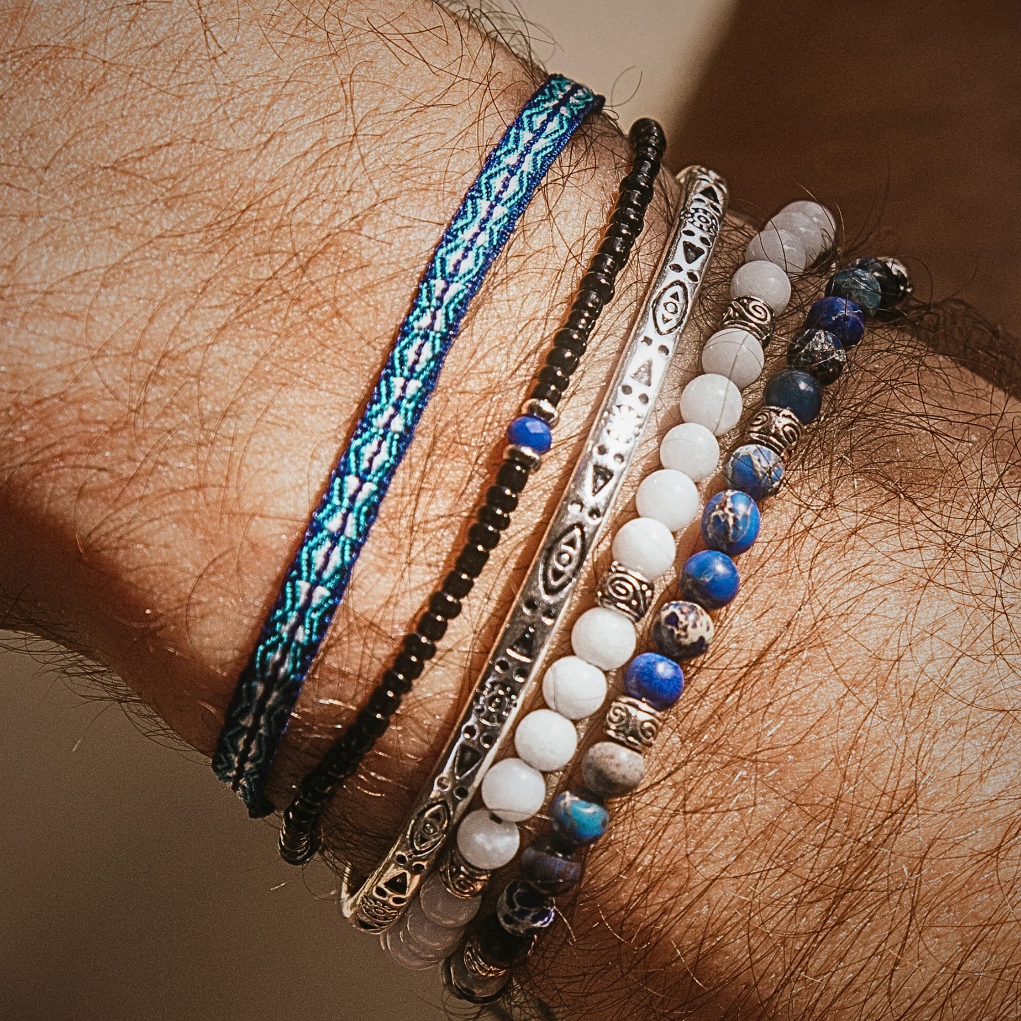 Detailed view of blue, black, and metal bracelet stack on wrist.
