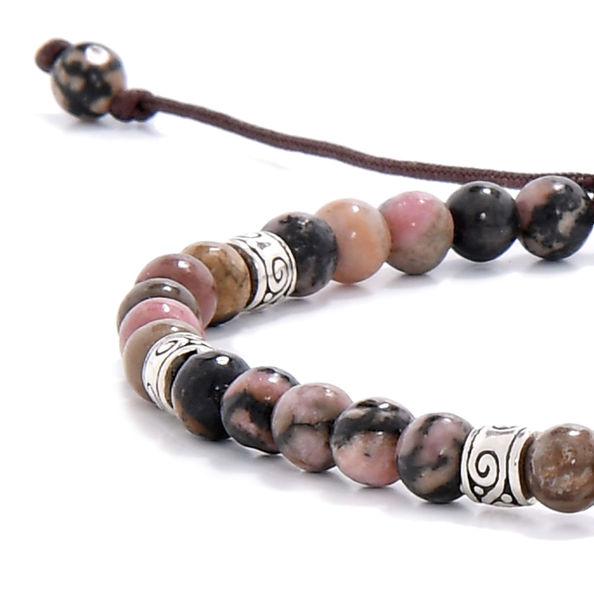 Zoomed-in section of a rhodonite bracelet showing the blend of pink, earthy hues, and metallic spacer details on a dark brown cord.