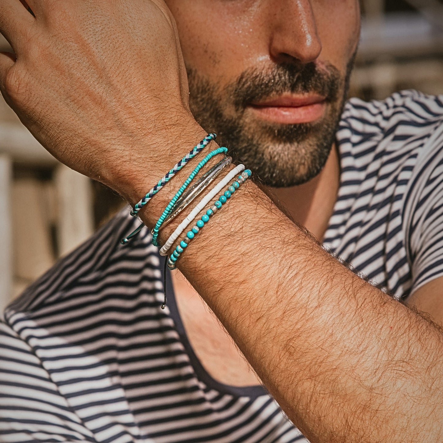 Man in a striped shirt displaying the full Positano bracelet set, styled with a coastal summer outfit.