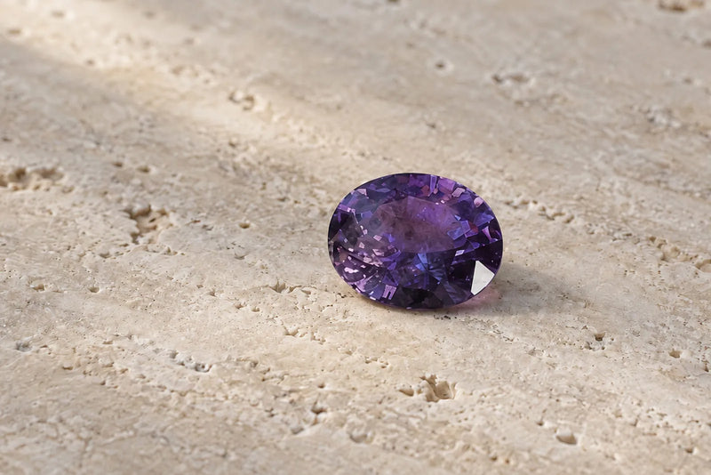 Faceted purple sapphire gemstone with deep violet color and oval cut