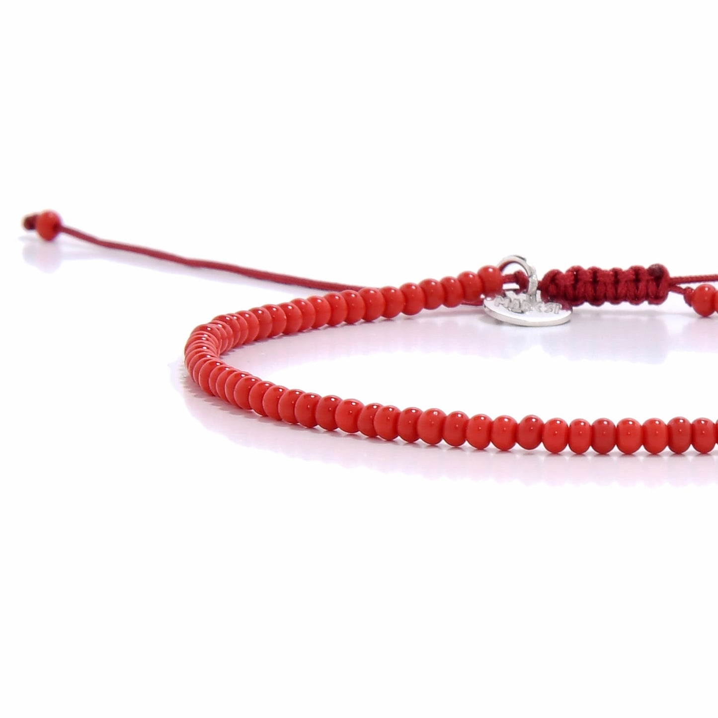 Angled view of red seed bead bracelet with silver charm for men beaded bracelets