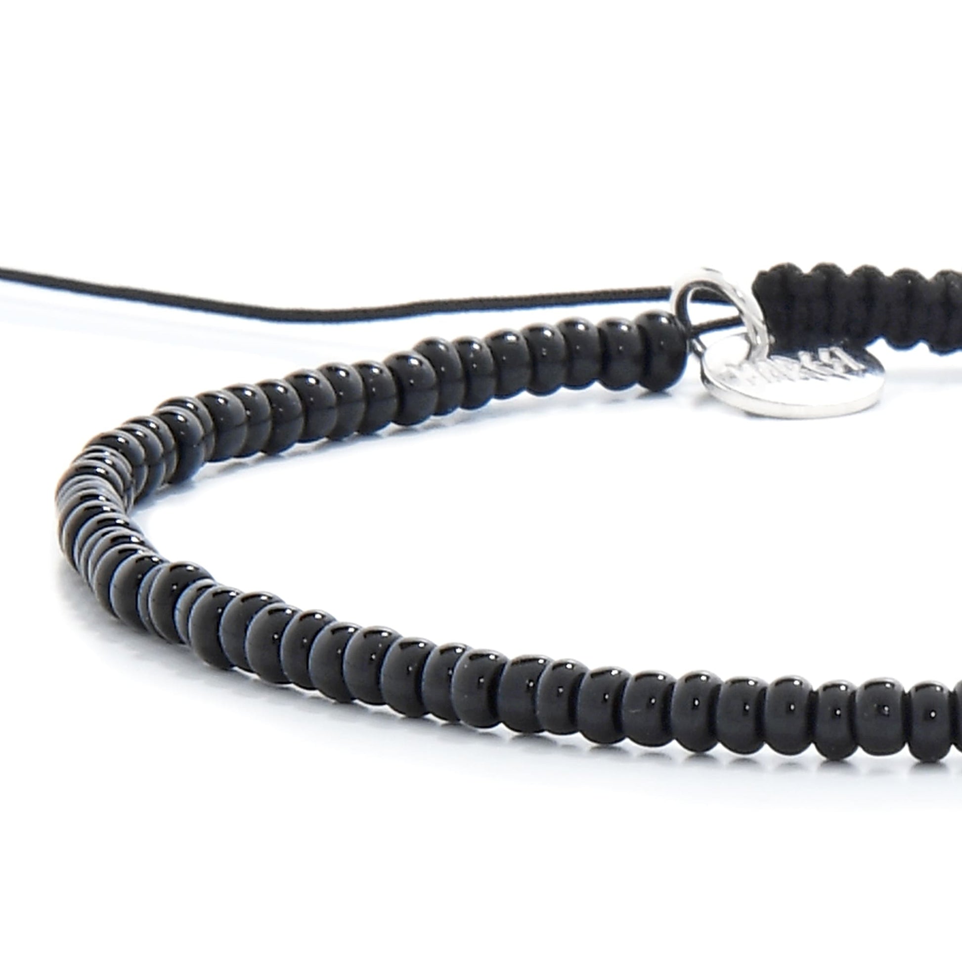 Angled side shot of black bead bracelet showing cord and charm