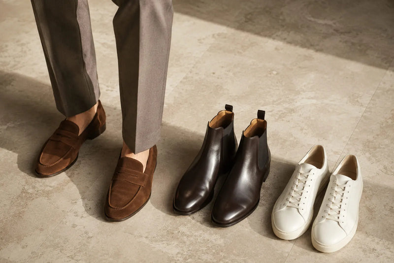 Brown suede loafers, dark Chelsea boots and minimalist white sneakers shown as footwear options for smart casual men.