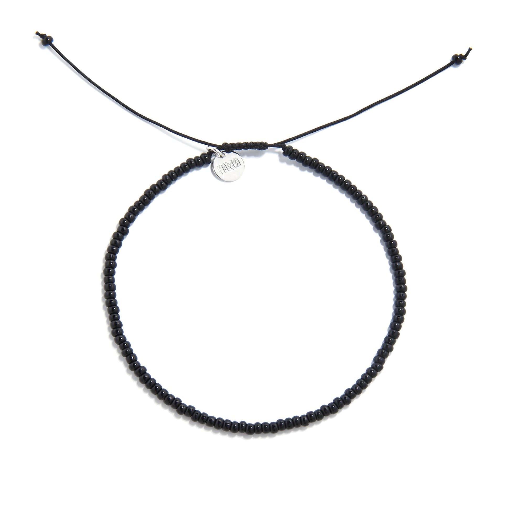 A top-down shot of a black bead bracelet forming a circle, showing a silver charm and adjustable cord ends.