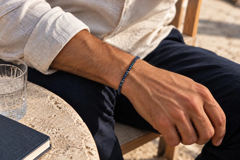 Beading Seed Beads: slim blue bead bracelet worn with a white linen shirt and navy trousers.