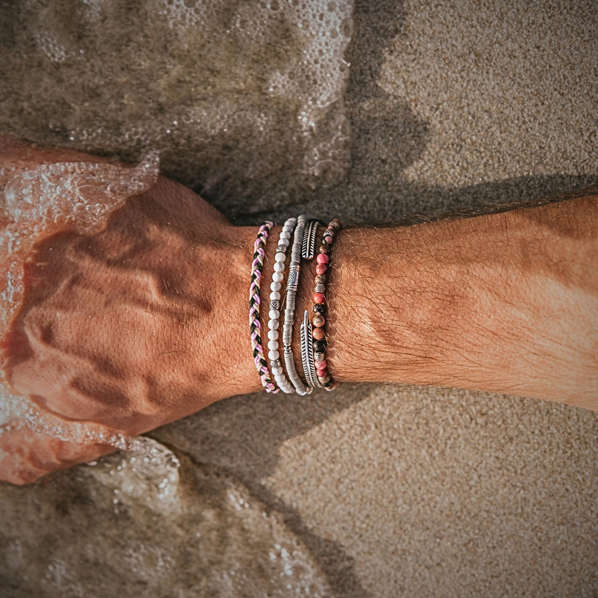 Wrist with Mallorca couples bracelet set in ocean water, showing colorful beads and silver stack.