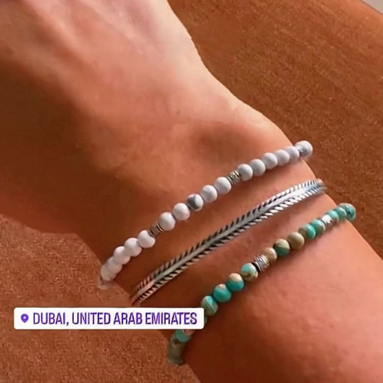 Bracelets on a wrist with a sandy background and 'Dubai, United Arab Emirates' text.