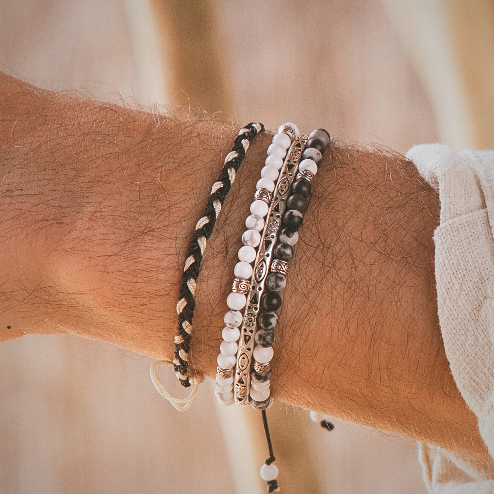 Side view of Palma silver bracelet set on wrist, showing braided cord and stacked beaded