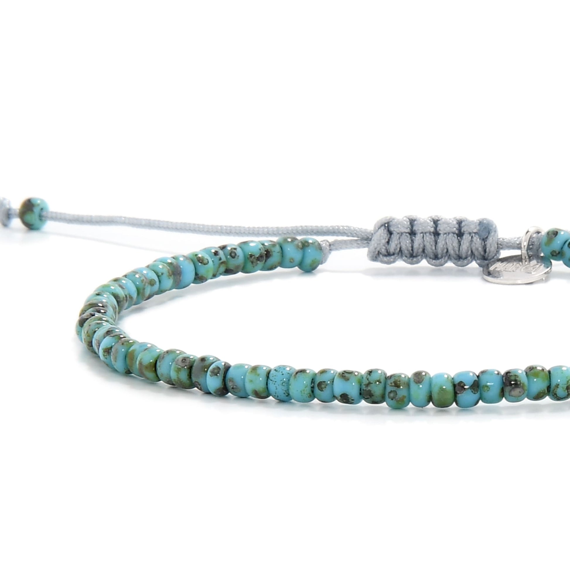 Side view of handmade bead bracelet featuring grey cord and earthy blue-green tones