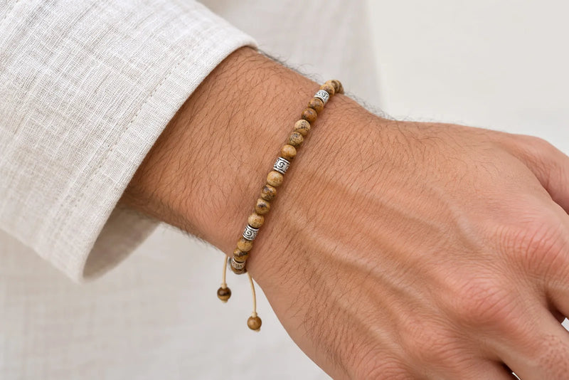 Small Beads in a Finished Bracelet Small beige and brown round beads with silver-colored spacers on a cord bracelet worn on a wrist.