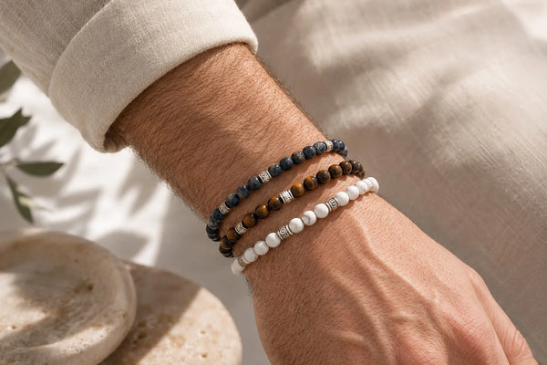 Best Stones for Men’s Bracelets shown as blue, tiger’s eye, and white beaded bracelets styled on a man’s wrist.