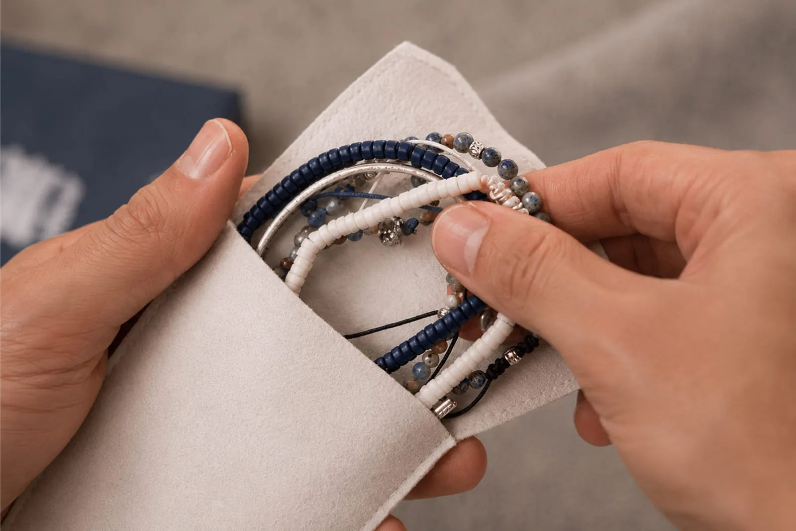 Bracelet care basics showing a man placing blue, white and gemstone bracelets into a soft protective pouch.