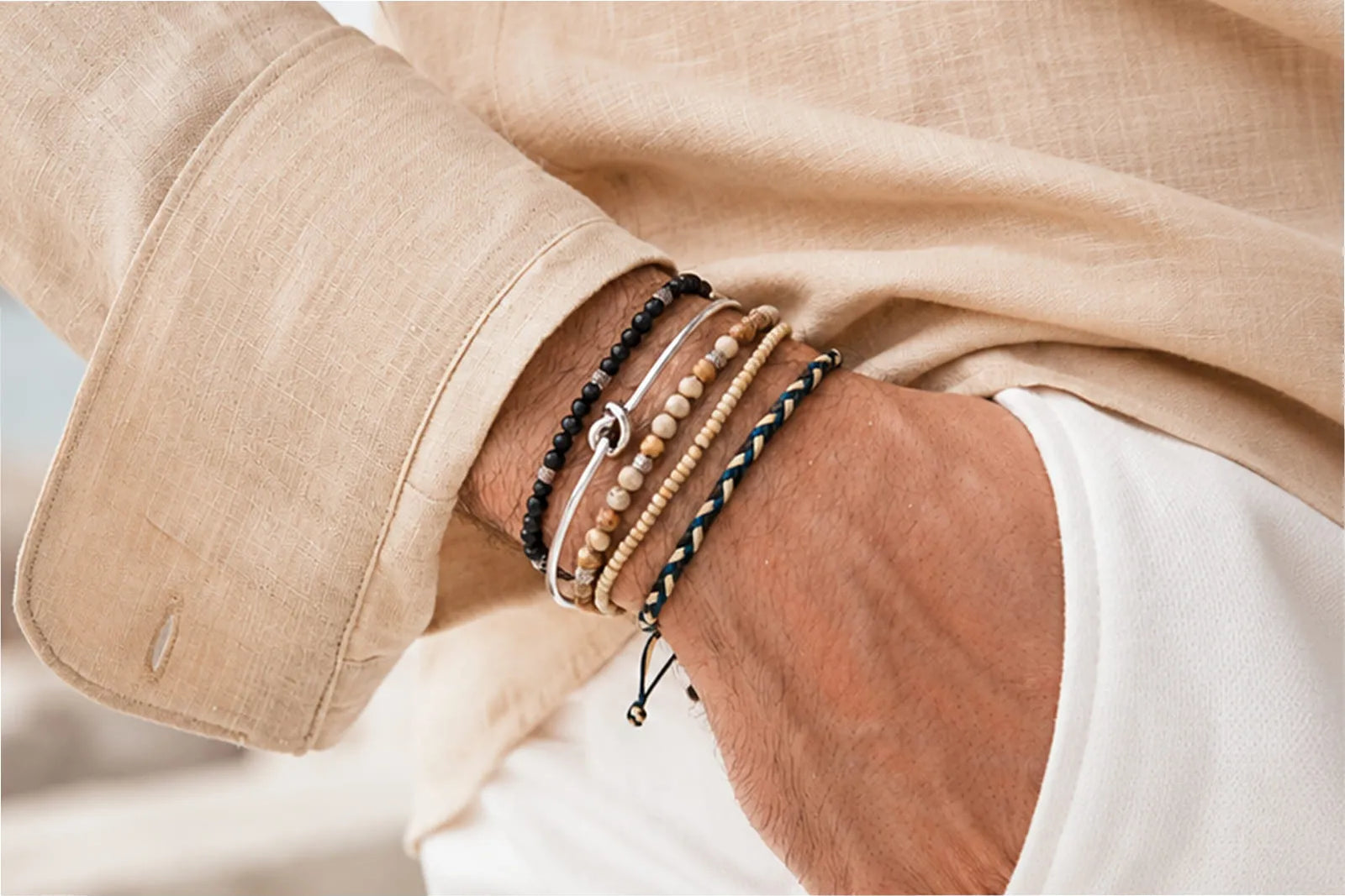 Can You Wear a Gemstone Bracelet Every Day, shown with a men’s stack of stone, silver, seed bead and woven bracelets.