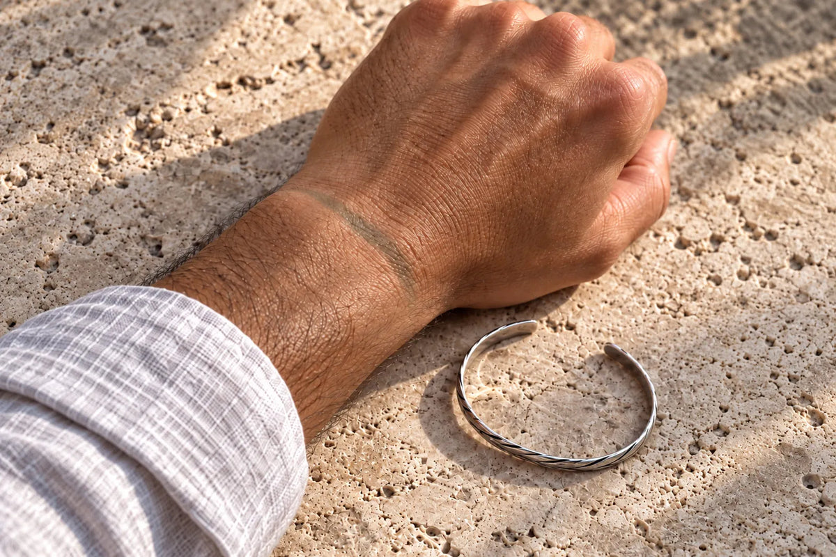 Does sterling silver turn green? A subtle green mark on a man’s wrist beside a silver bracelet.