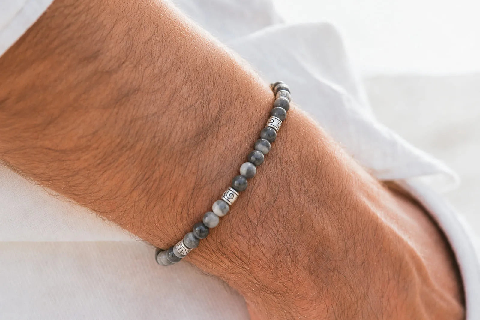 Gray Stone Jewelry for men featuring a slim beaded bracelet with silver spacers, styled against a crisp white shirt.