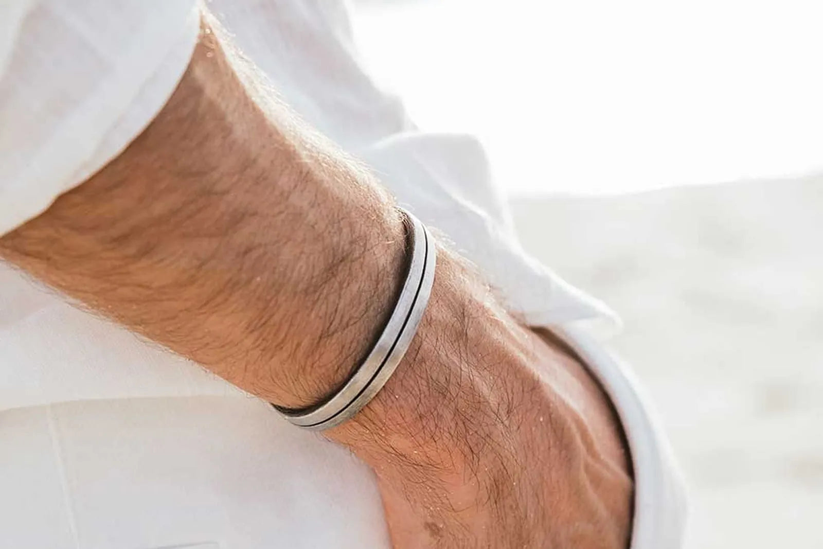 How do you wear a cuff bracelet? A silver cuff rests naturally just above a man’s wrist bone.