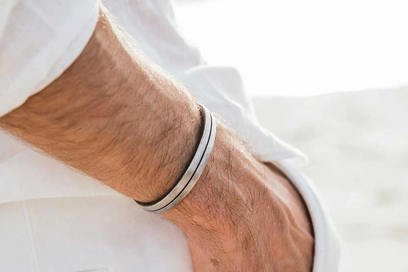 How do you wear a cuff bracelet? A silver cuff rests naturally just above a man’s wrist bone.