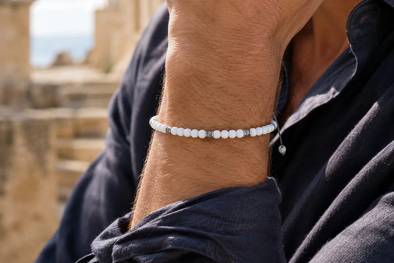Man wearing a white jade bead bracelet with silver details in a Mediterranean setting