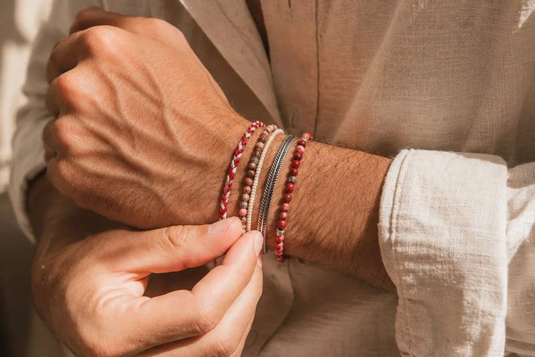 Jasper jewelry for men featuring layered red and neutral stone bracelets styled with a beige linen shirt.