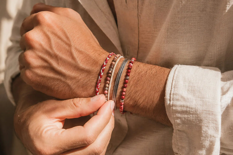 Jasper jewelry for men featuring layered red and neutral stone bracelets styled with a beige linen shirt.