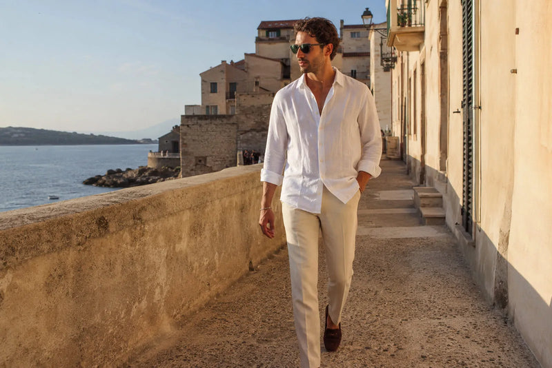 Man wearing a white linen shirt, cream trousers and brown loafers for a relaxed Mediterranean vacation outfit