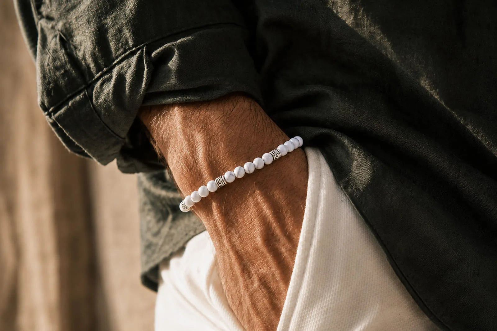 Real white howlite or fake bracelet comparison featuring white stone beads with subtle gray veining on a man’s wrist.