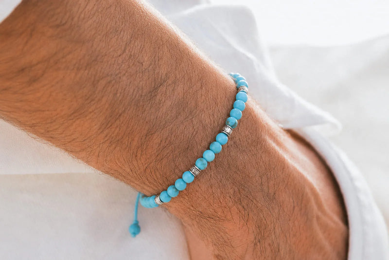 Turquoise bracelet for men with small blue beads and silver accents worn with a relaxed white shirt