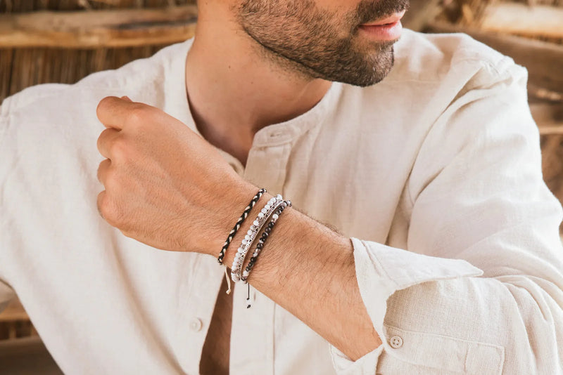 Which Wrist Should Men Wear a Bracelet On? Man styling stacked beaded and woven bracelets with a white linen shirt.