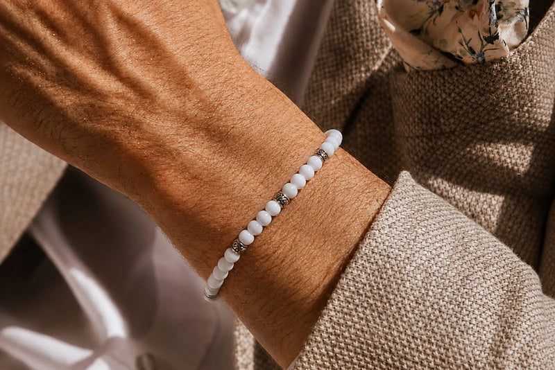 White Jade Bracelet Price shown through a slim white beaded bracelet with silver spacers, styled with a beige suit.