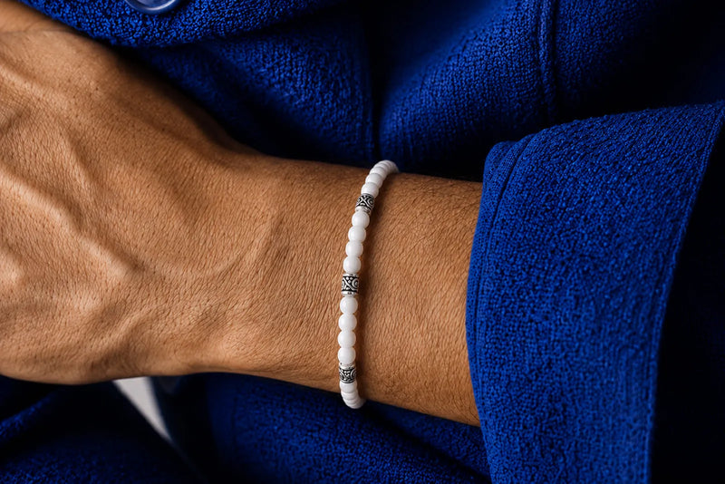White Jade Jewelry for men featuring a slim beaded bracelet with silver spacers, styled with a rich blue outfit.