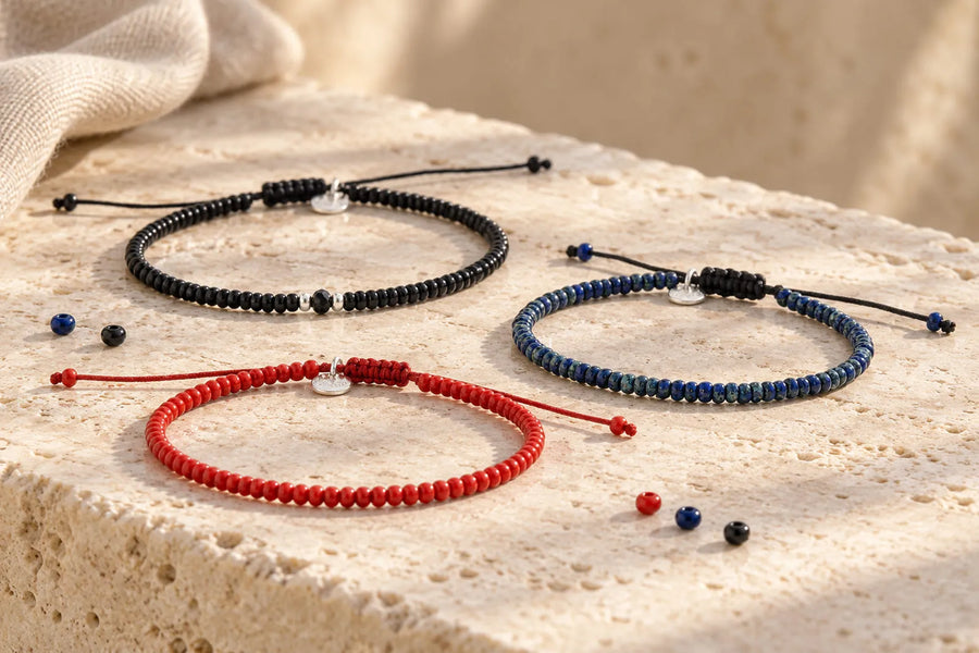 Beading Seed Beads: black, blue and red cord bracelets with adjustable closures on a pale stone surface.