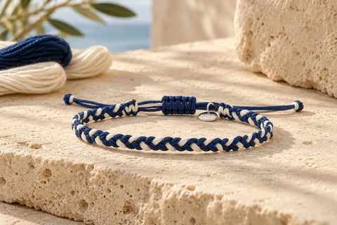 Navy and cream braided friendship bracelet with an adjustable knot and round charm on a stone surface